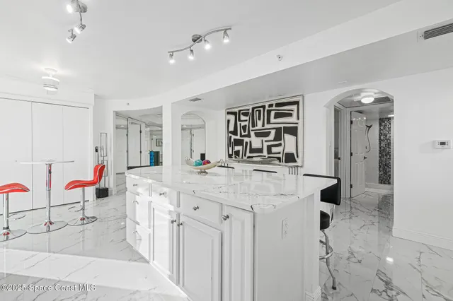 a spacious kitchen with stainless steel appliances kitchen island granite countertop a table and chairs in it