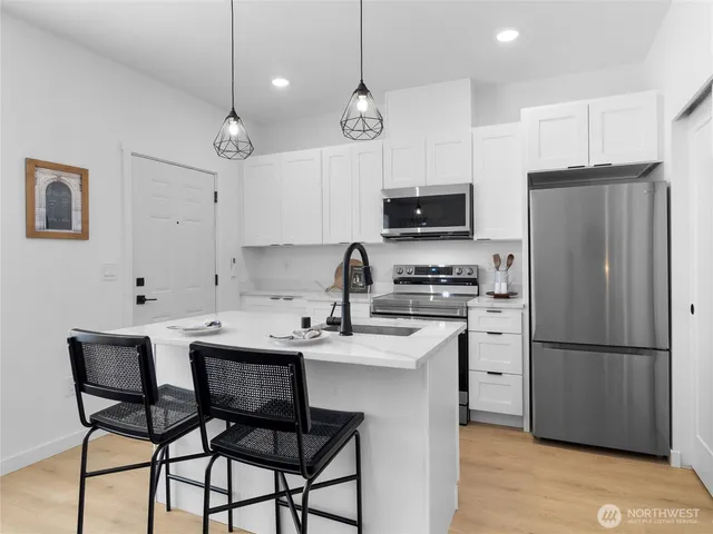 a kitchen with stainless steel appliances granite countertop a sink a stove and a refrigerator