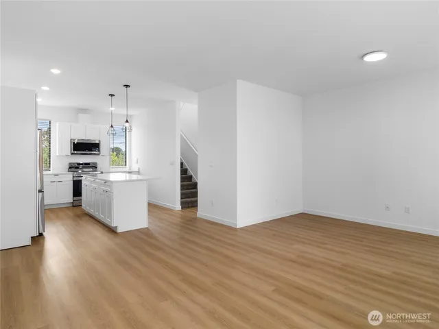 a kitchen with refrigerator a stove and wooden floor