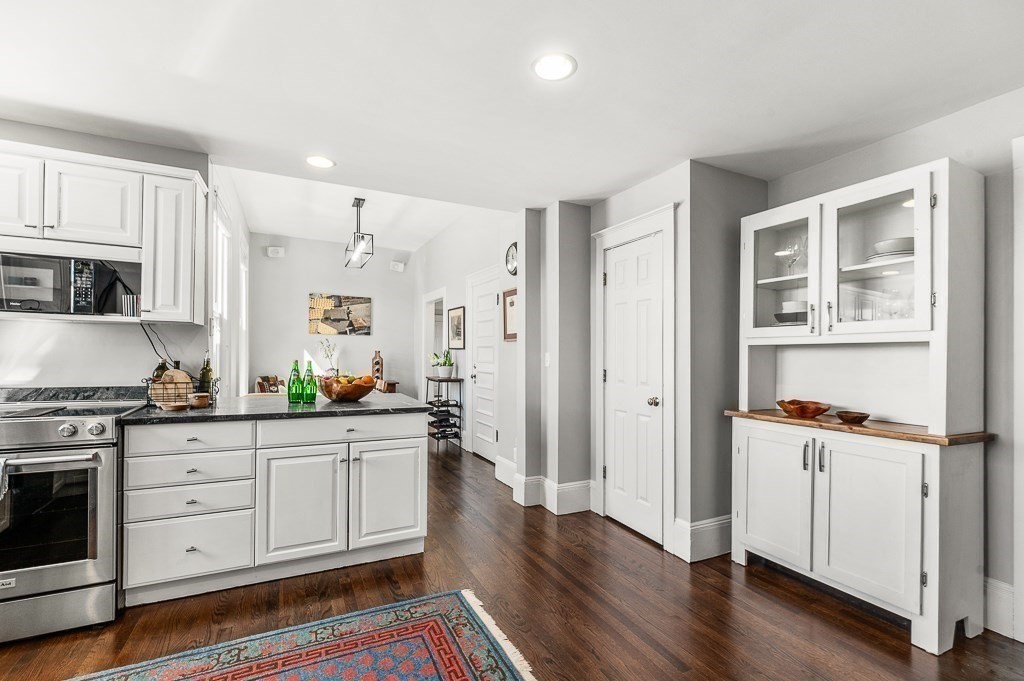 5 Babson Street, Unit 2 Gloucester, MA 01930 - Photo 13 of 30 a kitchen with white cabinets and wooden floor