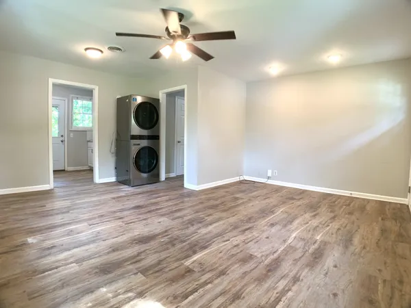 an empty room with wooden floor and windows