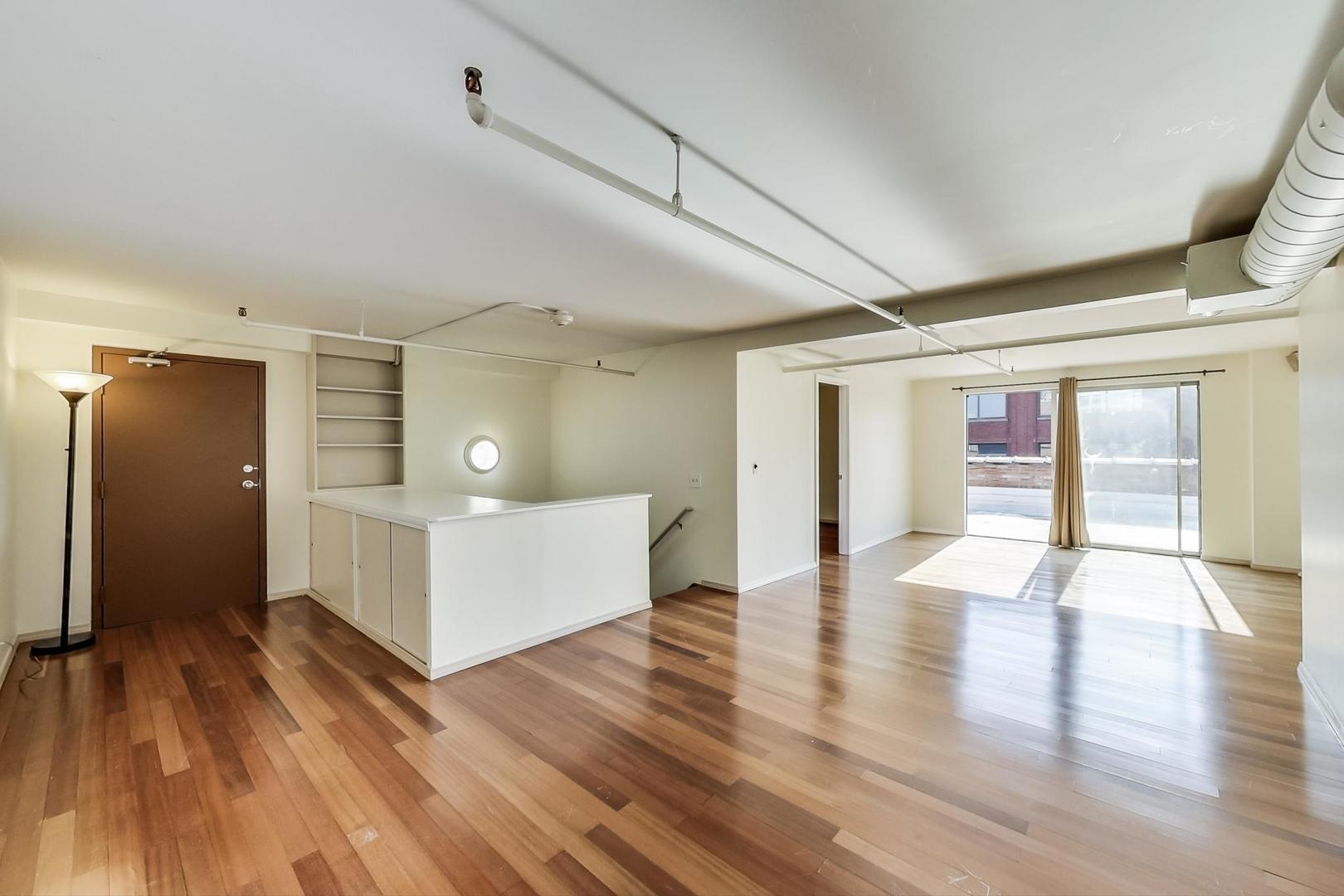 331 South Peoria Street, Unit 502 Chicago, IL 60607 - Photo 17 of 32 a view of an empty room with wooden floor and kitchen view