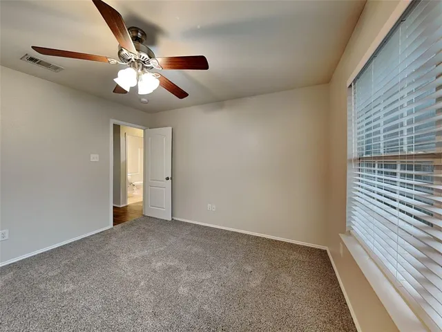 an empty room with chandelier fan and windows