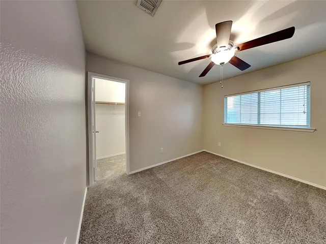 an empty room with a chandelier fan and windows