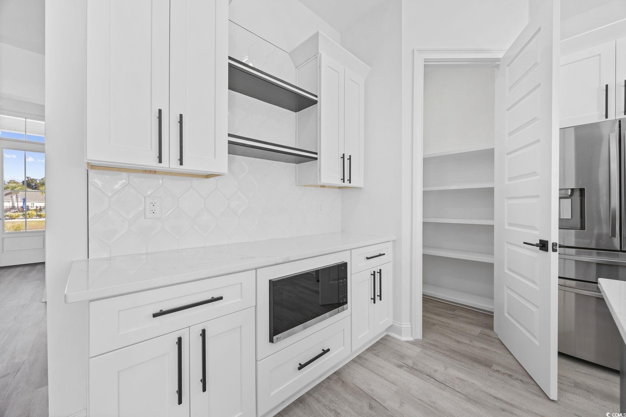 125 Lac Courte Myrtle Beach, SC 29579 - Photo 18 of 40 Kitchen featuring light stone countertops, appliances with stainless steel finishes, decorative backsplash, light wood-type flooring, and white cabinets