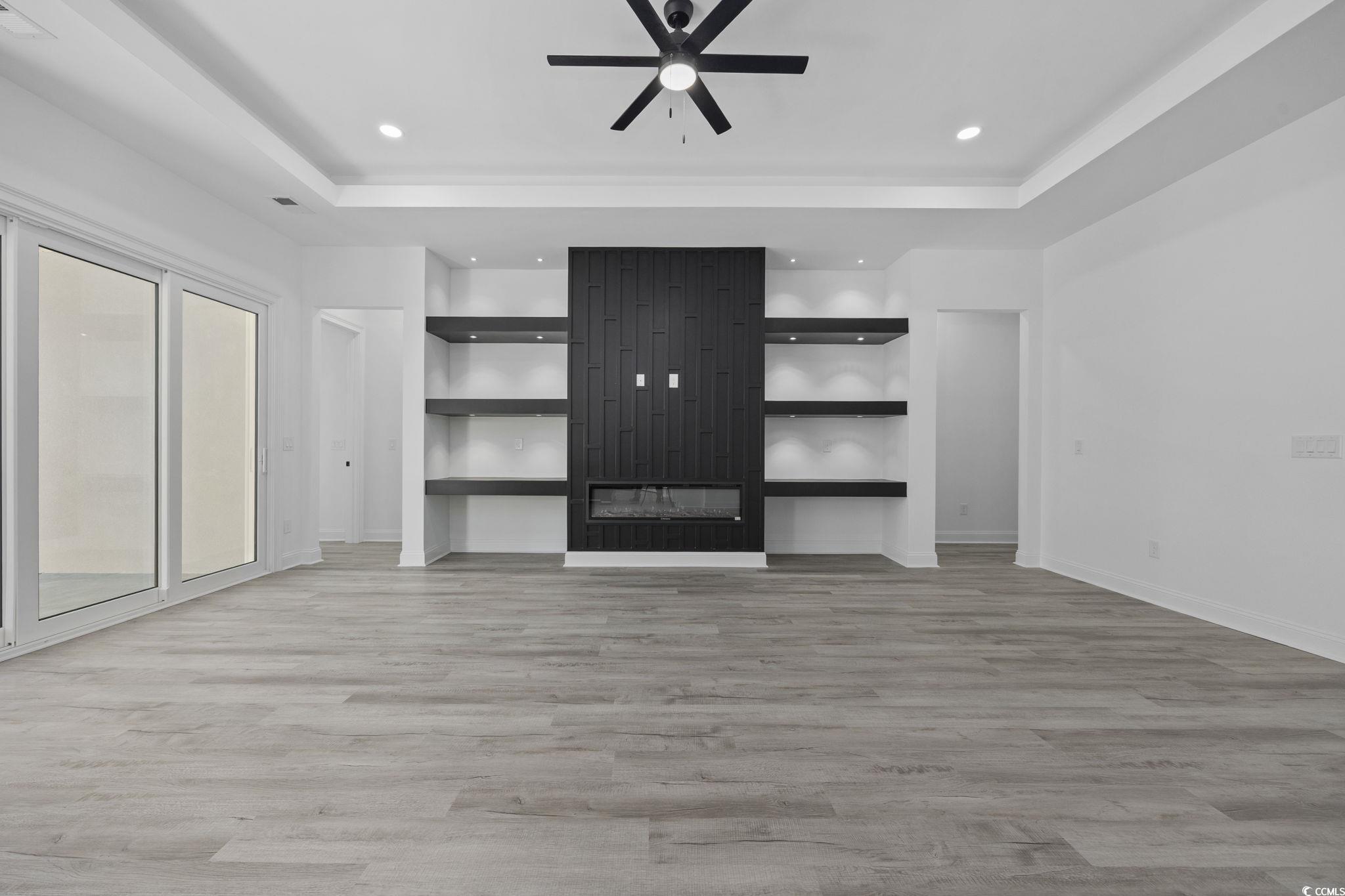 125 Lac Courte Myrtle Beach, SC 29579 - Photo 9 of 40 Unfurnished living room with a raised ceiling, light wood-style flooring, a large fireplace, ceiling fan, and recessed lighting