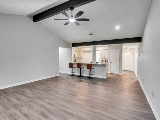 a view of an empty room with window and wooden floor