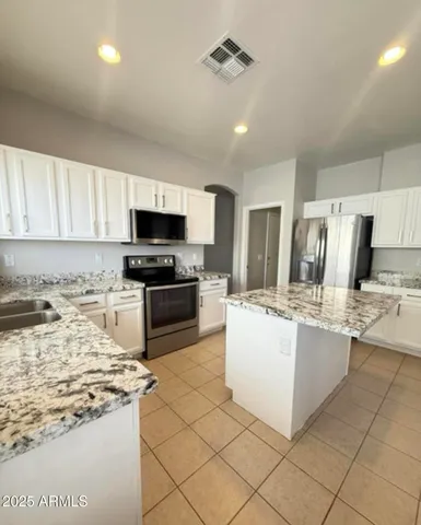 a kitchen with granite countertop a stove top oven a sink a counter top space and cabinets