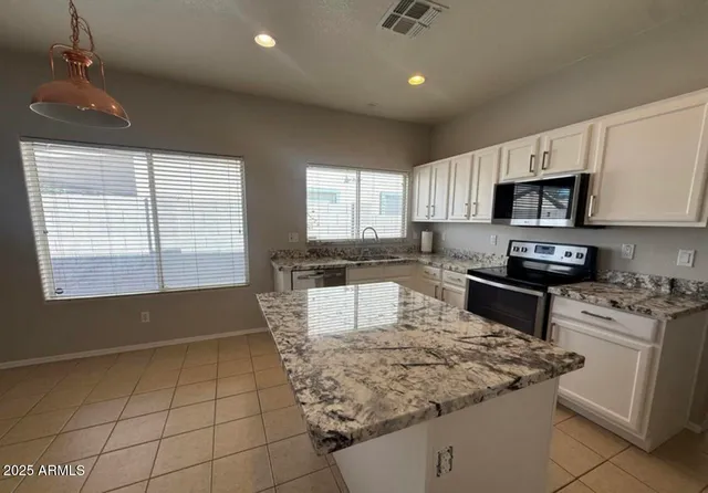 a kitchen with granite countertop a stove sink and microwave