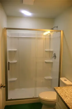 a bathroom with a granite countertop shower and a toilet