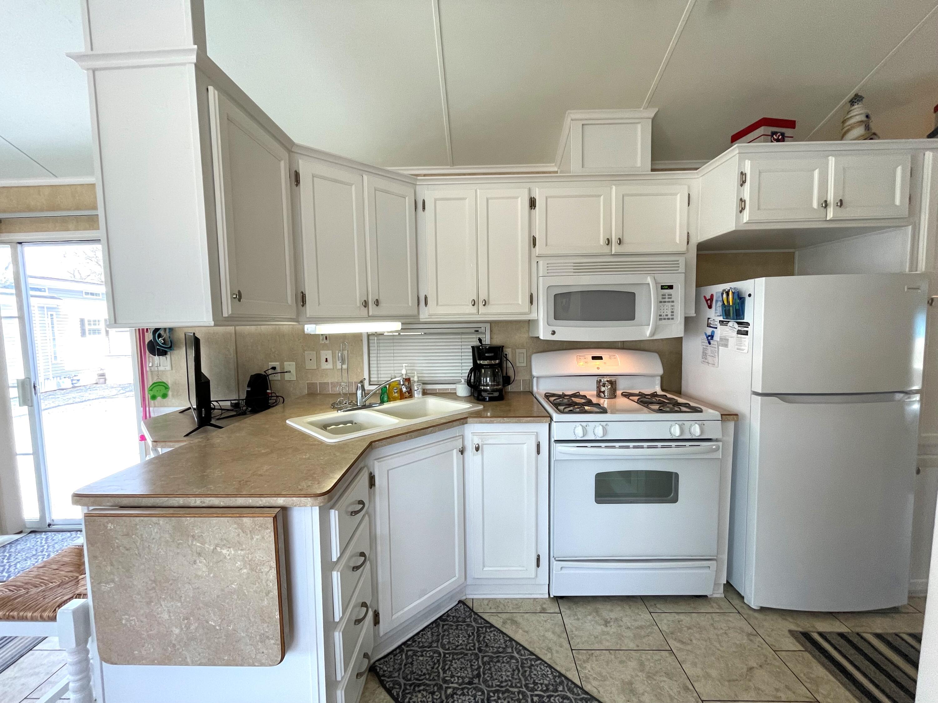 184 Old Wharf Road, Unit G05 Dennis Port, MA 02639 - Photo 5 of 17 a kitchen with stainless steel appliances granite countertop a refrigerator sink stove and white cabinets