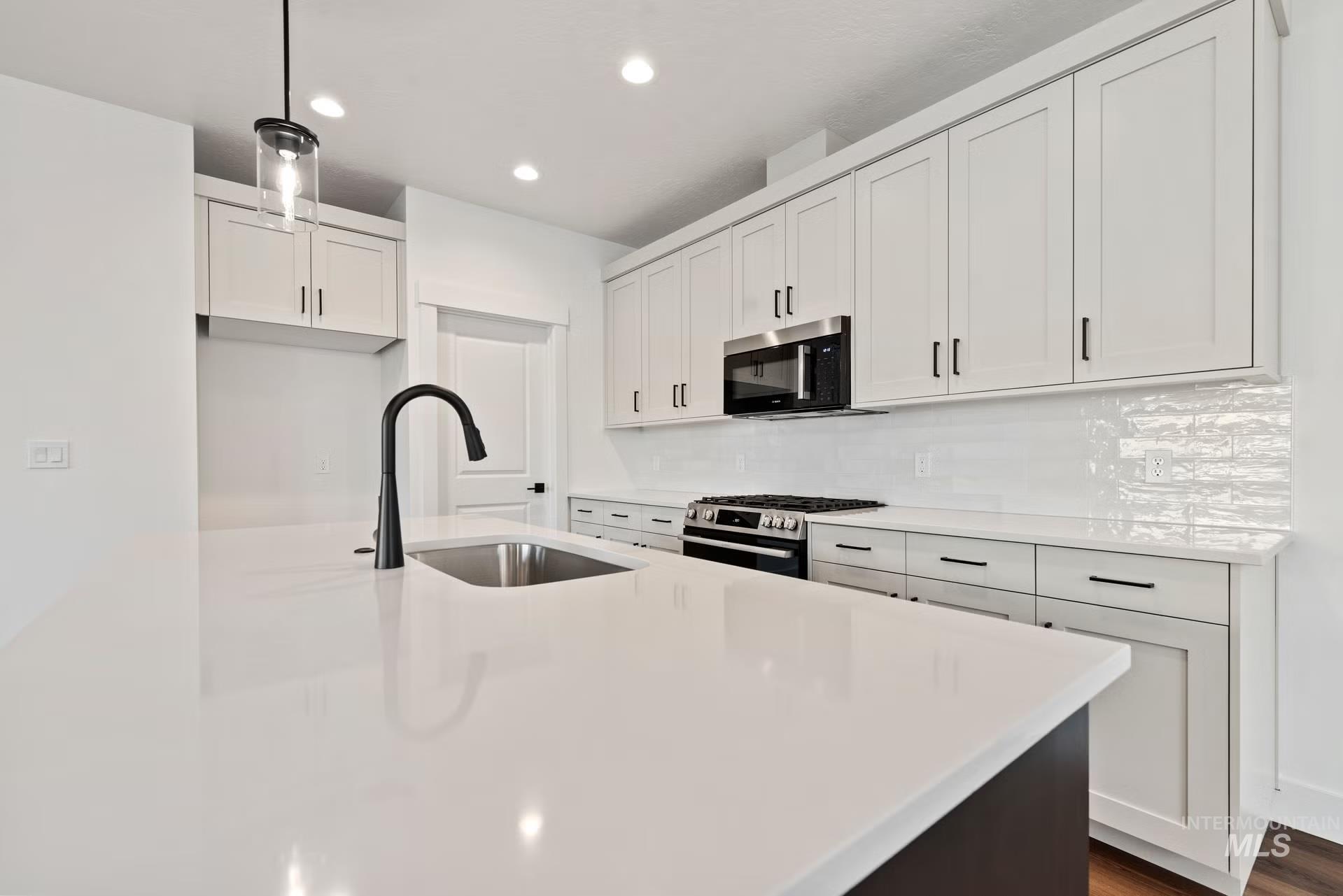 748 South Calhoun Place Star, ID 83669 - Photo 15 of 32 Kitchen with white cabinetry, stainless steel appliances, light stone counters, tasteful backsplash, and an island with sink