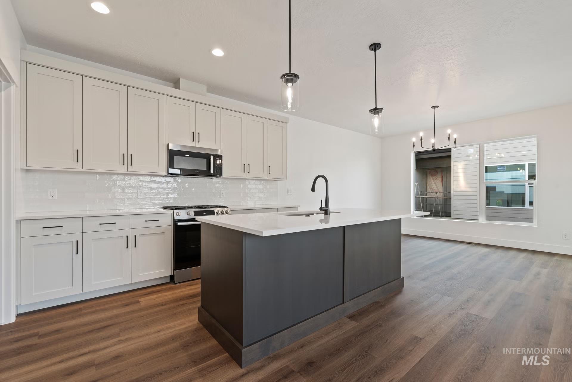 748 South Calhoun Place Star, ID 83669 - Photo 3 of 32 Dual tone kitchen featuring stainless steel appliances, tasteful backsplash, two tone cabinetry, a center island with sink, and a chandelier