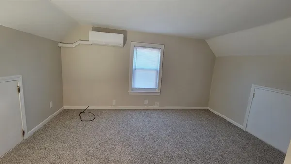a view of an empty room with closet and a window