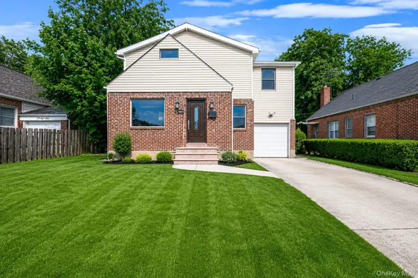 a front view of a house with a yard and trees