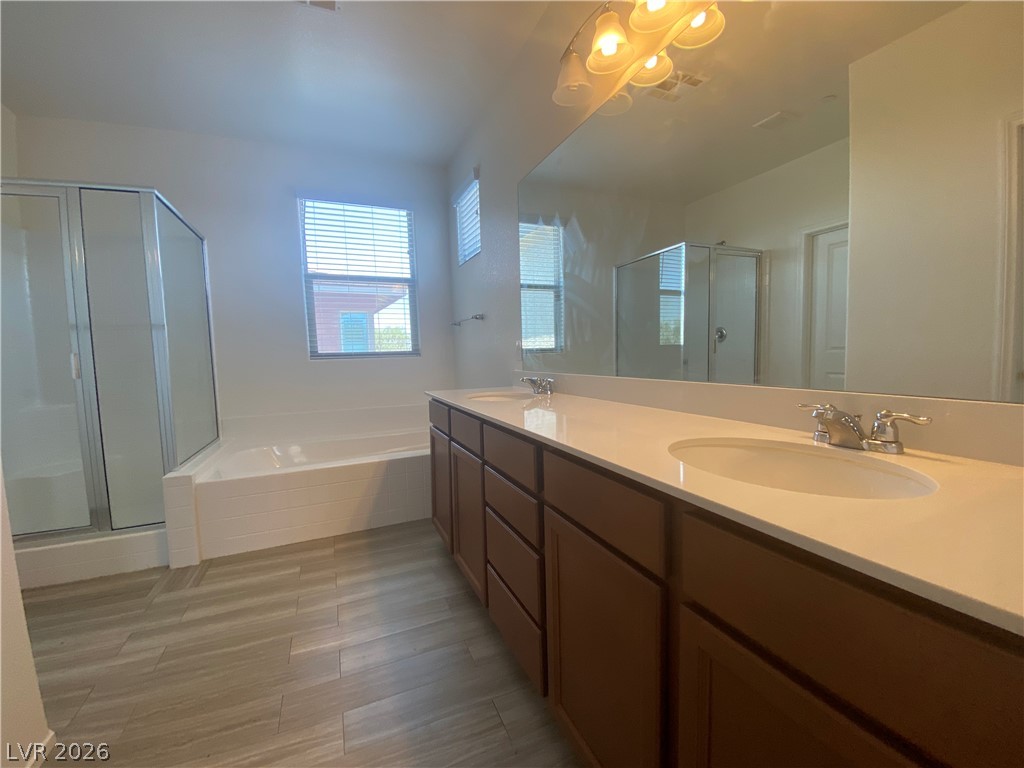 436 Cadence View Way Henderson, NV 89011 - Photo 28 of 36 A well-lit primary bathroom provides a spacious vanity with dual sinks, a large soaking tub, and a separate glass-enclosed shower.