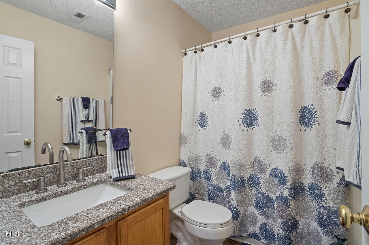 7040 Bellard Court Raleigh, NC 27617 - Photo 19 of 31 a bathroom with a granite countertop sink toilet and shower