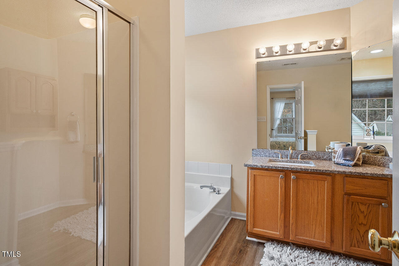 7040 Bellard Court Raleigh, NC 27617 - Photo 26 of 31 a en suite bathroom with a granite countertop sink a mirror and a shower