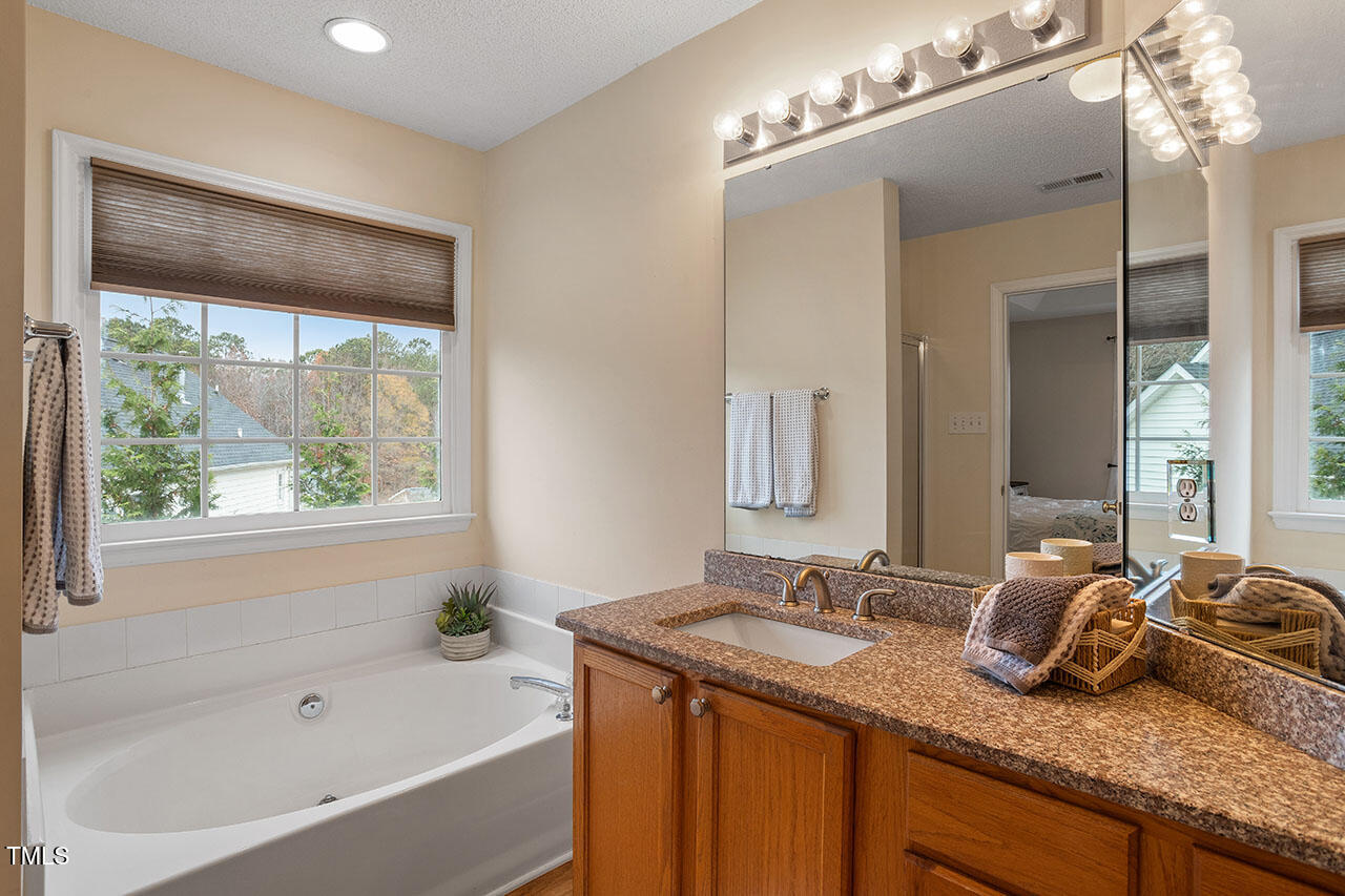 7040 Bellard Court Raleigh, NC 27617 - Photo 27 of 31 a bathroom with a granite countertop sink mirror and a bathtub
