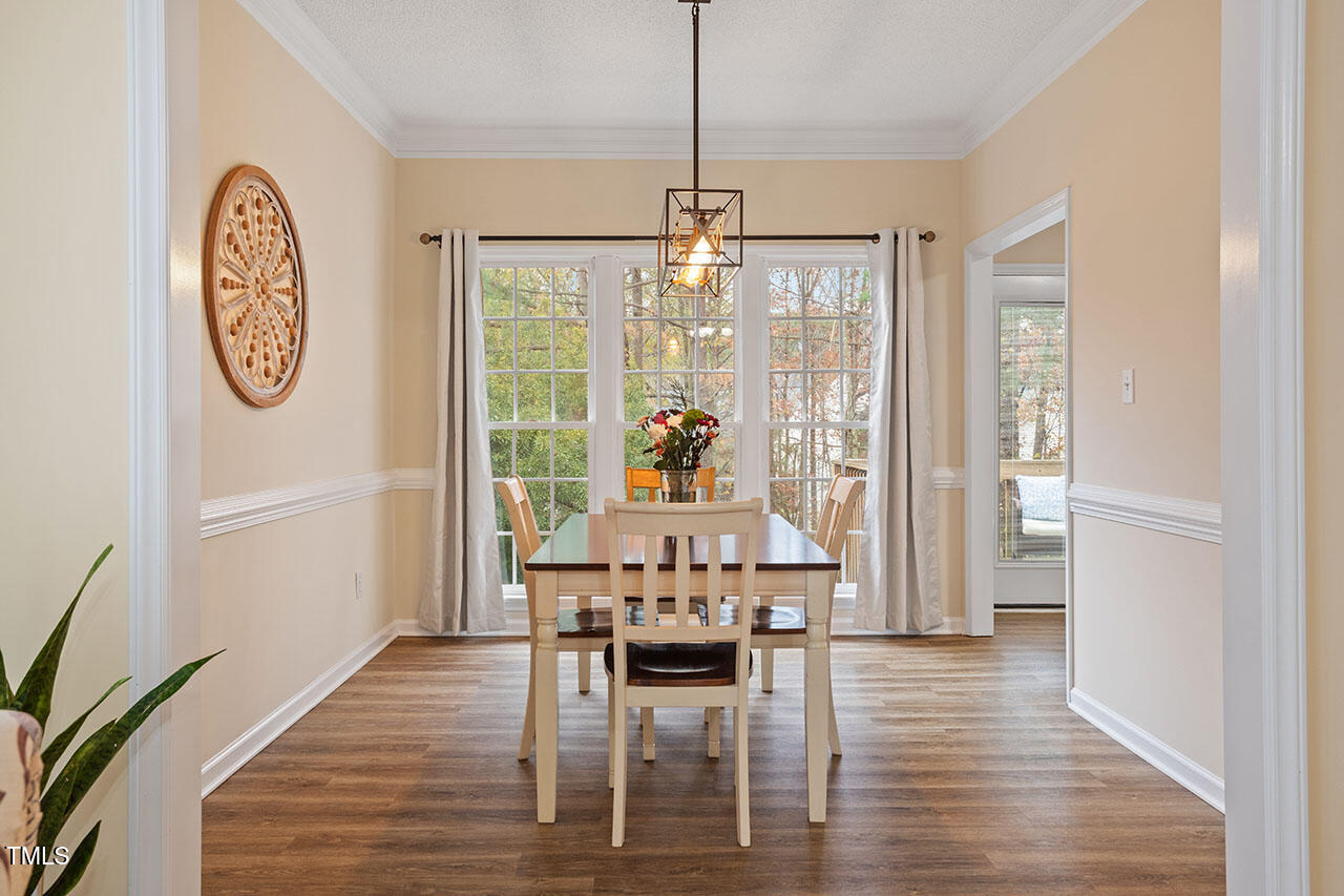 7040 Bellard Court Raleigh, NC 27617 - Photo 9 of 31 a dining room with furniture a chandelier and wooden floor
