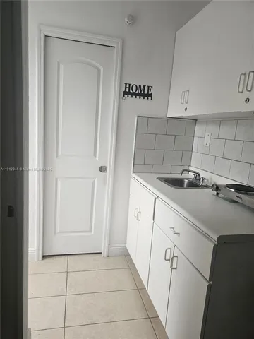 a view of a refrigerator in kitchen and an empty room
