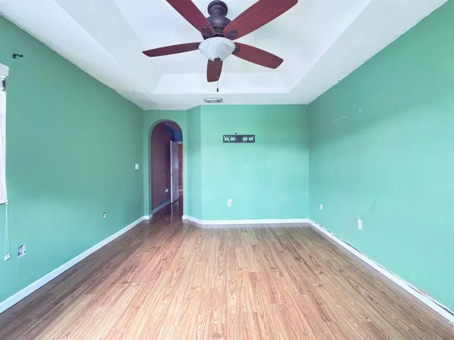 a view of a room with wooden floor a ceiling fan and window