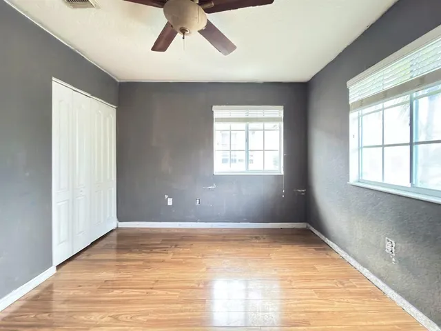 a view of an empty room with wooden floor and a window