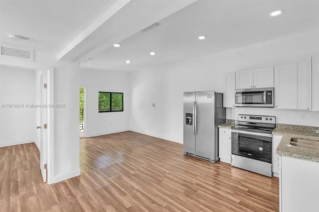 a view of kitchen with stainless steel appliances refrigerator stove microwave and cabinets