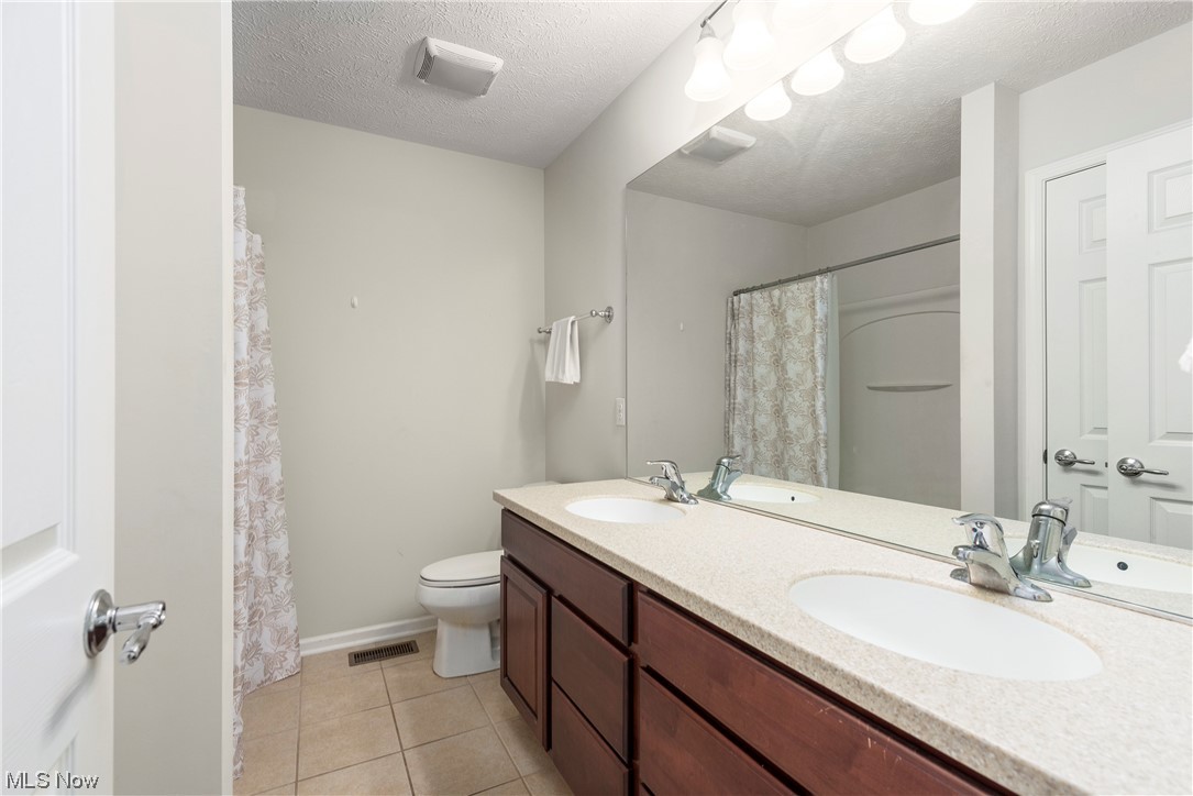3967 Gardiner Run Akron, OH 44321 - Photo 24 of 35 Master bathroom featuring light tile floors, dual vanity, mirror, and a textured ceiling