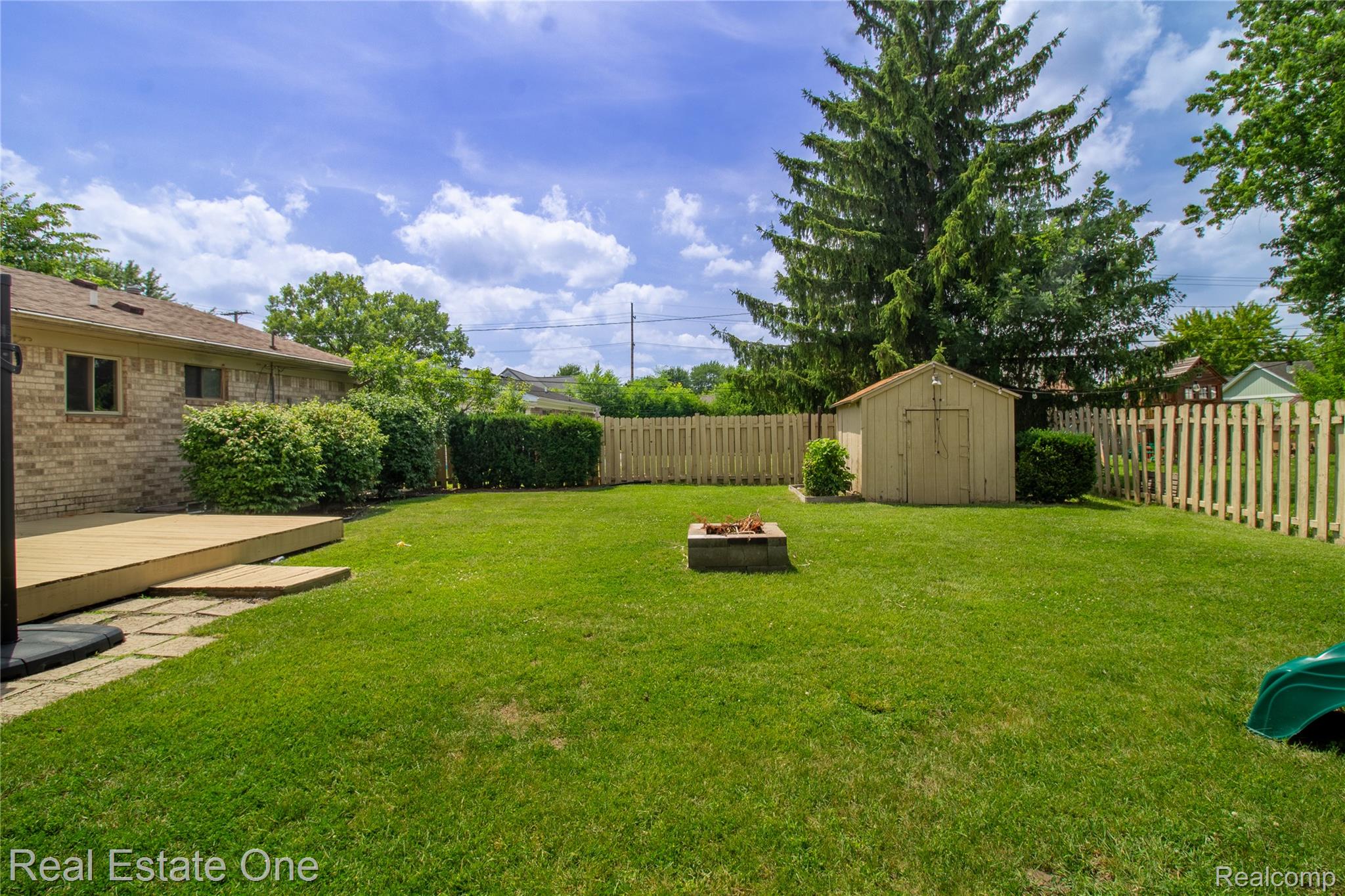 44220 Saltz Road Canton, MI 48187 - Photo 20 of 31 Spacious backyard featuring a wood-finish deck, brick exterior, wood privacy fencing, and a storage shed