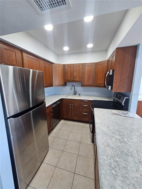 14800 Walsingham Road, Unit 1215 Largo, FL 33774 - Photo 7 of 26 a kitchen with stainless steel appliances granite countertop a refrigerator and a sink