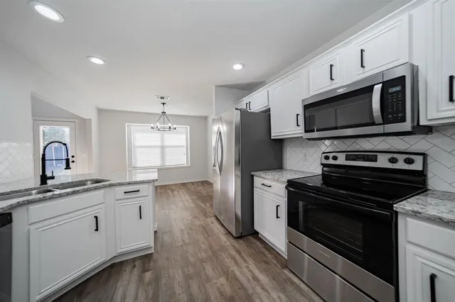 a kitchen with stainless steel appliances a stove microwave and sink