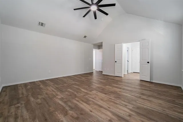 a view of an empty room with window and wooden floor