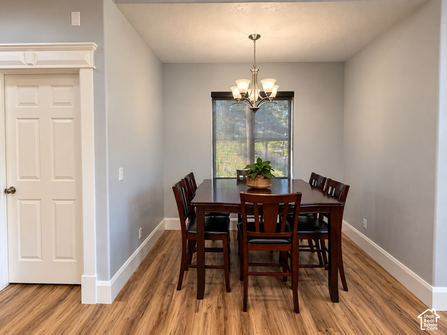 1750 West 4100 North Helper, UT 84526 - Photo 23 of 50 Dining area featuring wood-finish flooring, a contemporary chandelier, and a window with a roller shade