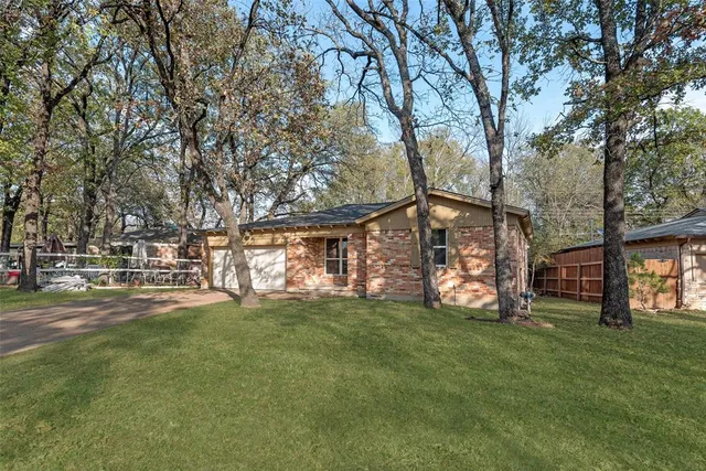 a view of a house with a big yard and large trees