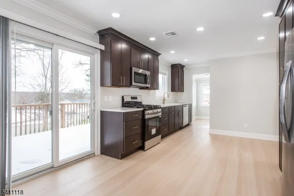 a large kitchen with stainless steel appliances lots of counter top space and wooden floor