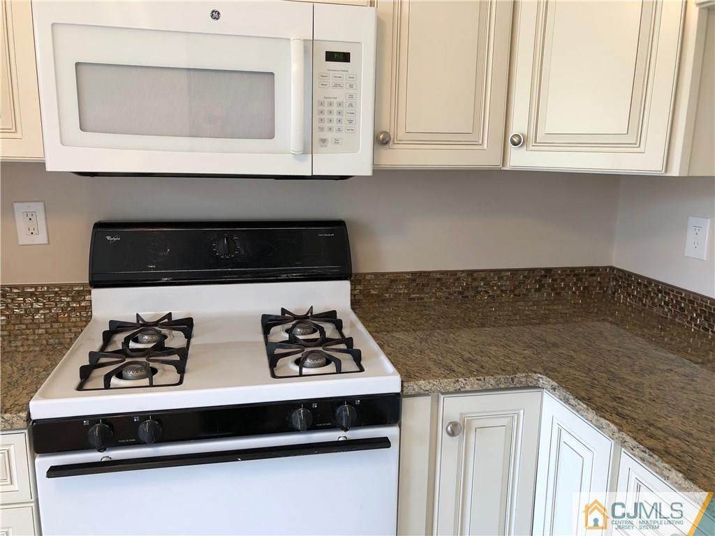 1804 Timber Oaks Road Edison, NJ 08820 - Photo 6 of 23 a kitchen with granite countertop a stove a microwave a sink and white cabinets