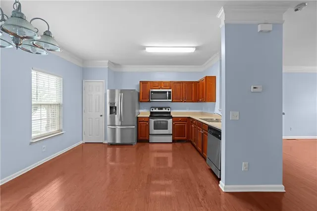 a large kitchen with stainless steel appliances a large counter top and a window