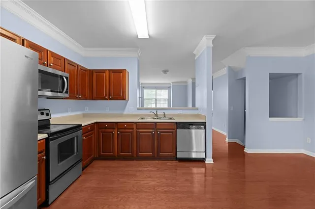 a large kitchen with stainless steel appliances granite countertop a stove a sink dishwasher and a microwave oven with wooden floor