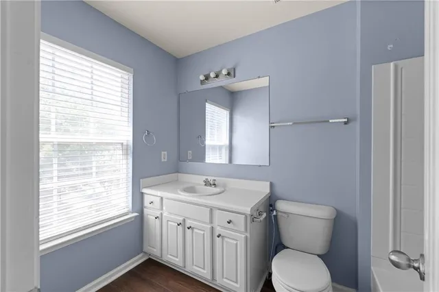 a bathroom with a toilet a sink a mirror and a window