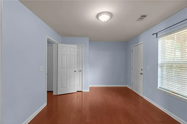 a view of empty room with wooden floor and fan