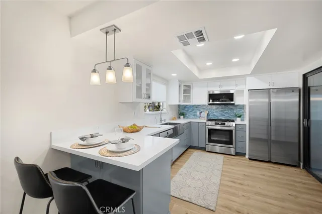 a kitchen with stainless steel appliances a stove a sink a microwave a dining table and chairs