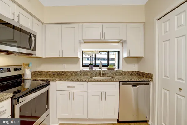 a kitchen with stainless steel appliances granite countertop a refrigerator a stove and a sink