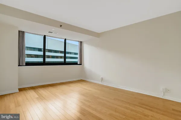 a view of an empty room with wooden floor and a window