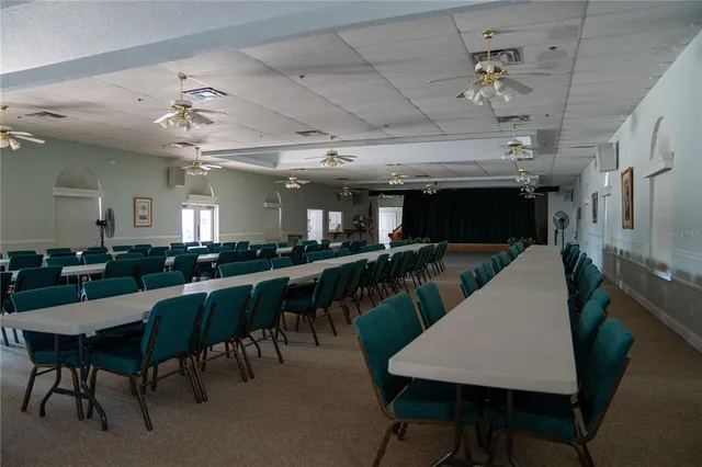 a dining hall with stainless steel appliances kitchen island granite countertop a dining table chairs and a counter top