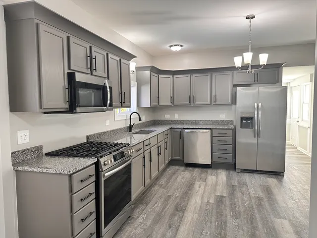 a kitchen with stainless steel appliances granite countertop a stove a sink dishwasher a refrigerator and a oven with wooden floor