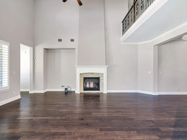 a view of an empty room with wooden floor fireplace and a window