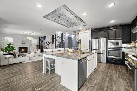 a kitchen with stainless steel appliances kitchen island granite countertop a large island in the center and wooden floors