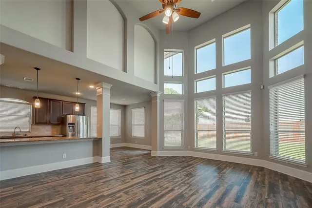 a view of an empty room with kitchen and window