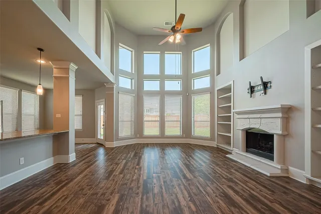 a view of an empty room with wooden floor fireplace and a window
